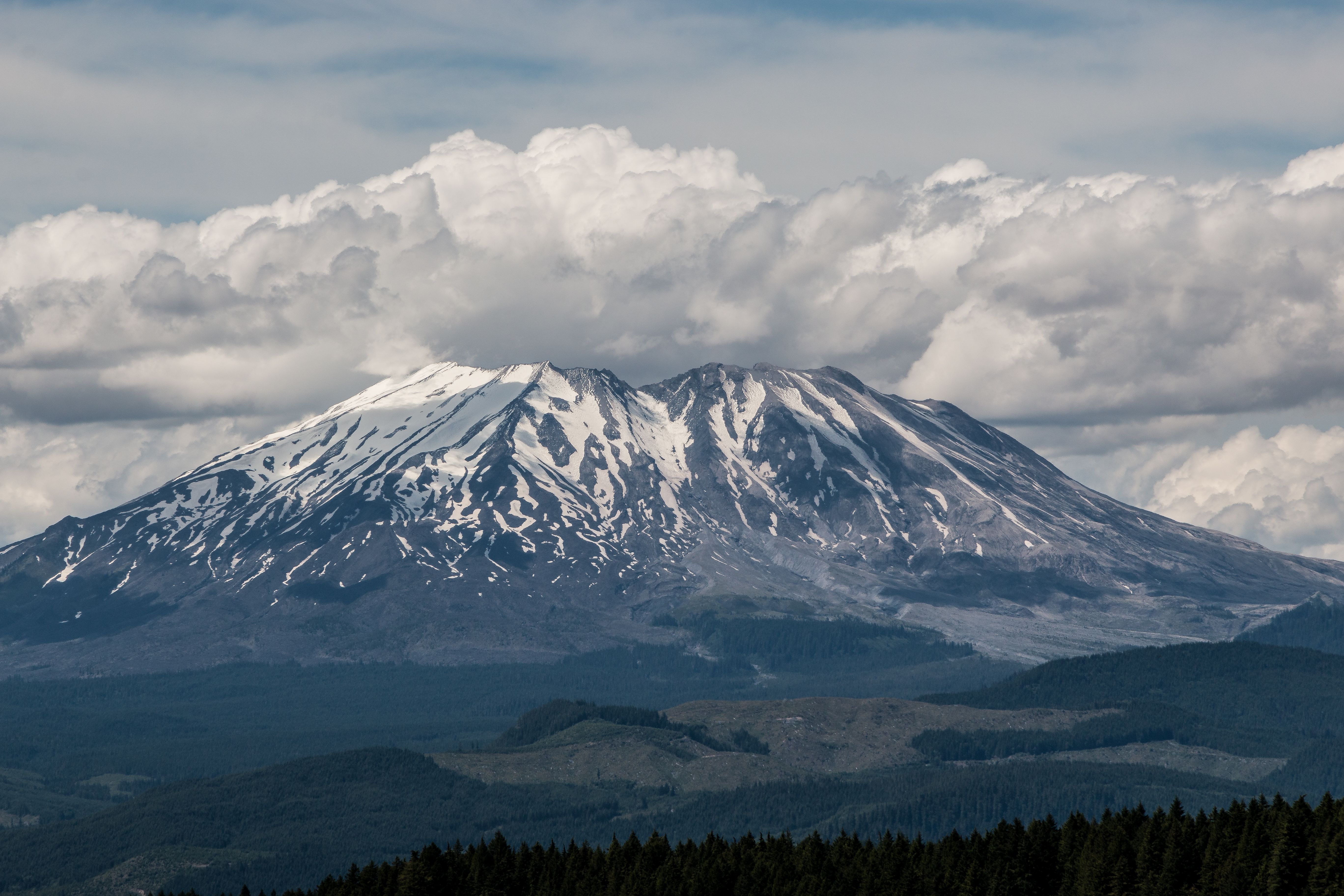 Snow-capped peak above layered evergreen ridges at dusk